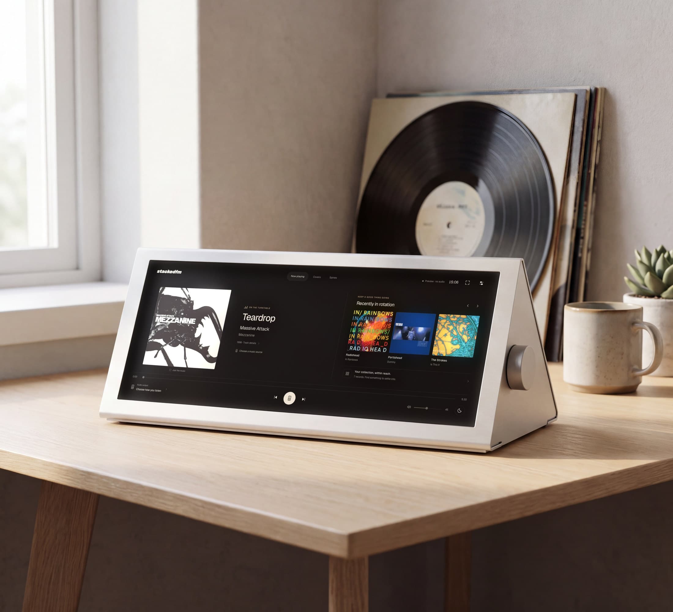 An AI-generated image: the StackedFM Prism, a wedge of white aluminium with a long touchscreen showing StackedFM and a volume knob on its right-hand end, on an oak desk by a window, with records leaning against the wall behind.