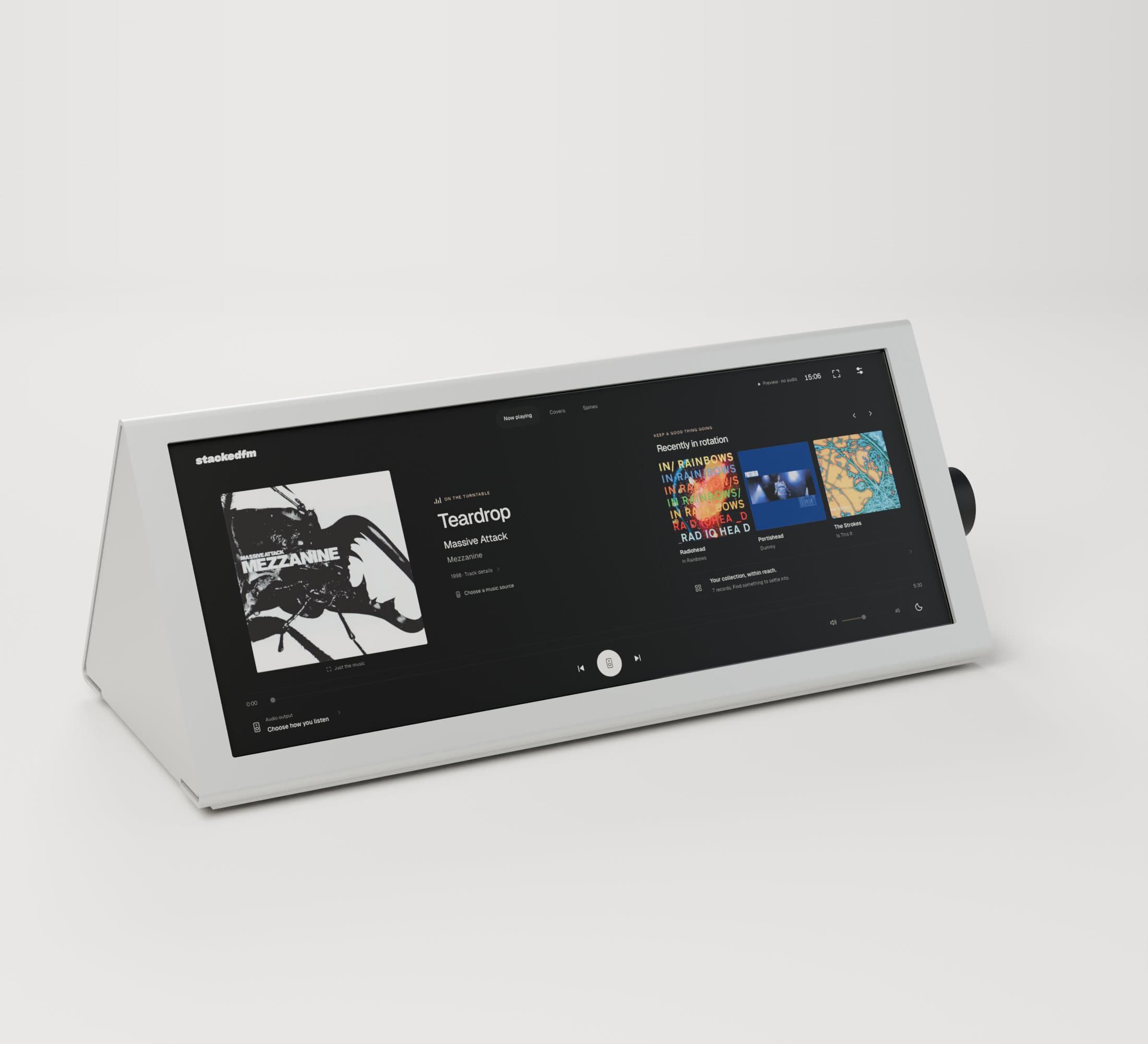 A render of the white aluminium enclosure from the front: a long touchscreen showing StackedFM, and the volume knob on its right-hand end.